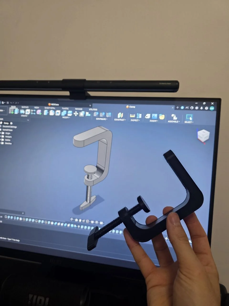 Fusion 360 model of the desk clamp on screen, next to the printed PETG part held in hand